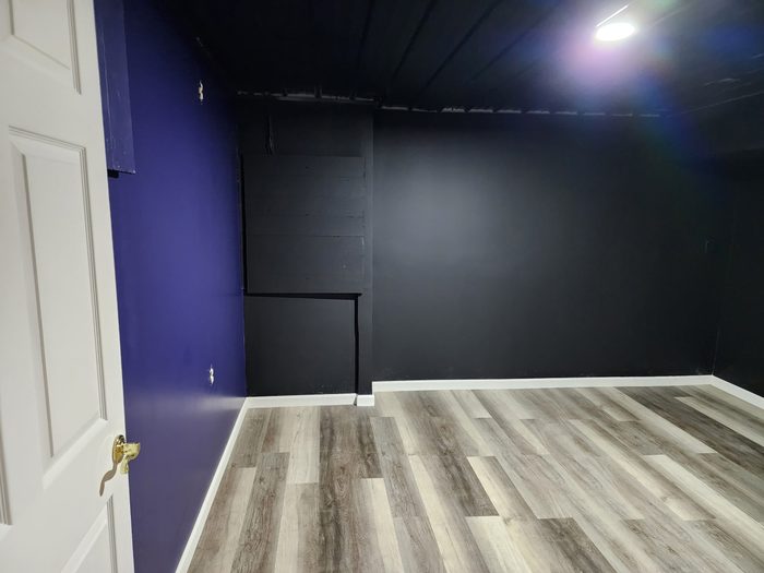 Basement room with navy accent wall and black walls and ceiling